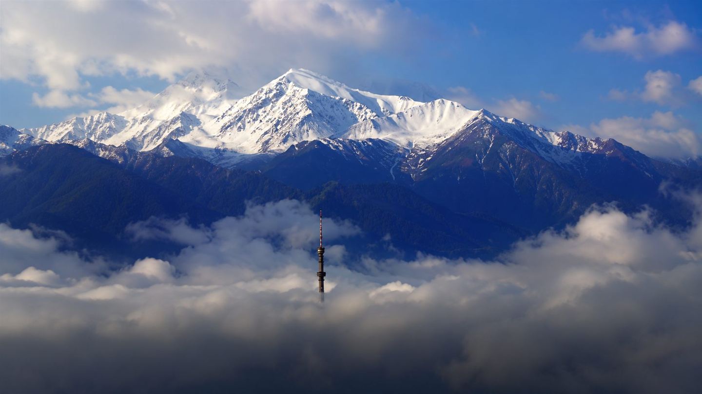Tian Shan peak and Kok-Tobe tower above the clouds